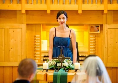 Frau in blauer Kleidung bei einer Hochzeit in Murnau. Kirchliche Trauung mit Blumen und Kerzen. Hochzeitsreportage.