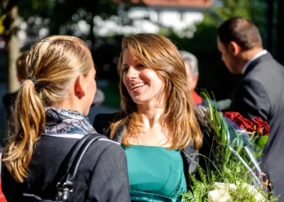 Lächelnde Gäste mit Blumenstrauß bei standesamtlicher Trauung in Pasing, Hochzeitsfotografie in München.