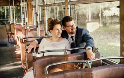Brautpaar laechelt in alter Tram bei Gruenwald, Hochzeitsfoto zeigt Glueck und Liebe im rustikalen Ambiente.