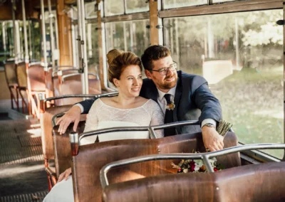 Brautpaar laechelt in alter Tram bei Gruenwald, Hochzeitsfoto zeigt Glueck und Liebe im rustikalen Ambiente.