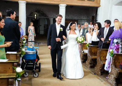 Brautpaar geht durch Kirchenschiff, Hochzeitsgaeste in Aufkirchen applaudieren, festliche Hochzeitsfotografie.