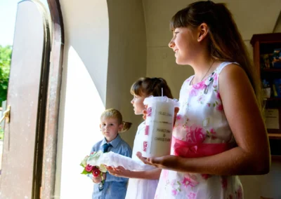 Kinder in festlicher Kleidung mit einer Kerze und Blumen bei einer kirchlichen Trauung in Taufkirchen bei München.