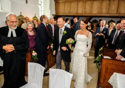 Brautpaar laechelnd bei kirchlicher Trauung in einer Kirche bei Freising, Brautstrauss in der Hand des Braeutigams.