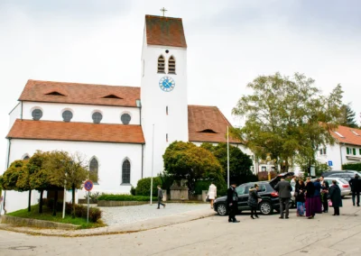 Kirchliche Trauung in St. Vitus Gilching mit Gästen vor der Kirche. Hochzeitsfotografie für unvergessliche Momente.