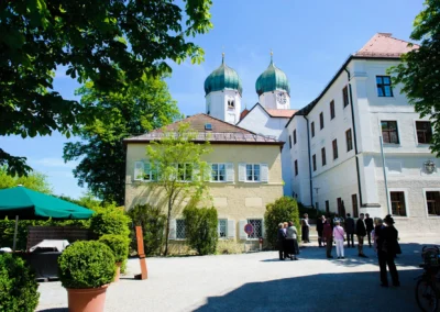 Garten des Klosters bei Hochzeitsreportage nahe des Chiemsees. Gäste versammeln sich vor der kirchlichen Trauung.
