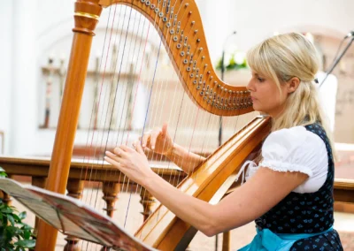 Harfenspielerin bei kirchlicher Trauung in Aufkirchen. Hochzeit in Oberbayern, festgehalten von einem Hochzeitsfotografen.