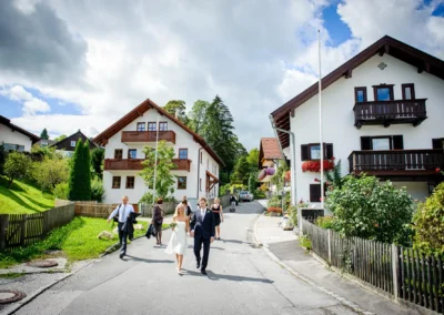 Brautpaar bei der standesamtlichen Trauung in Bernried am See, spaziert lächelnd durch eine malerische Dorfstraße.
