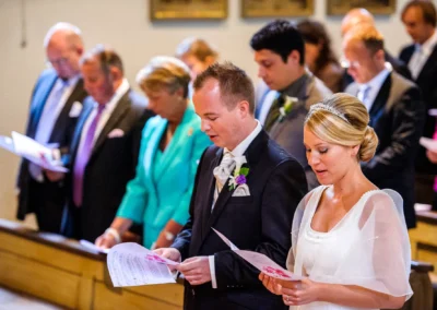 Brautpaar bei der kirchlichen Trauung in Muenchen, umgeben von Gaesten in feierlicher Stimmung. Hochzeitsfotografie.