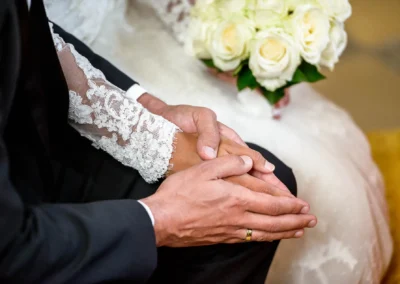 Brautpaar haelt Haende, Brautstrauss mit weissen Rosen, Kirchliche Trauung in Sankt Martin Waakirchen.