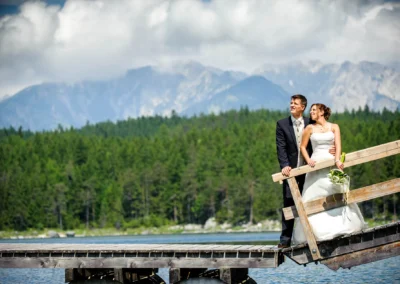 Brautpaar auf Steg am Eibsee mit Bergen im Hintergrund, Hochzeitsfoto, festgehalten bei einer Hochzeitsreportage.