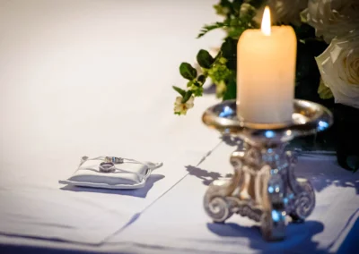 Kerzenleuchter und Ringkissen mit Trauringen bei kirchlicher Trauung in Pasing, detailreiche Hochzeitsfotografie.