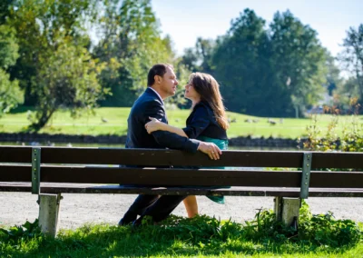 Paar auf einer Parkbank in München, umgeben von grünem Park. Hochzeitsreportage mit romantischem Moment im Freien.