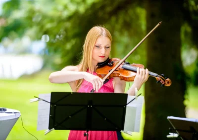 Violinistin spielt bei Hochzeit am Tegernsee. Hochzeitsfotografie mit Musikauftritt im Freien.