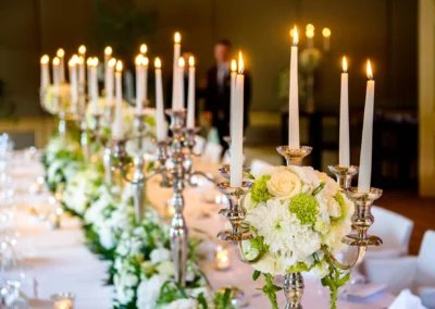 Kerzenleuchter und Blumenarrangements auf Hochzeitstisch im Hotel Ueberfahrt am Tegernsee bei Hochzeitsfeier.
