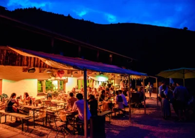 Hochzeitsfeier bei Nacht auf der Wuhrsteinalm im Chiemgau mit beleuchteter Terrasse und Gästen in festlicher Stimmung.
