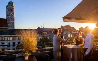 Gäste bei einer Hochzeitsfeier auf der Terrasse des Bayerischen Hofes in München, fröhlich beim Anstoßen.