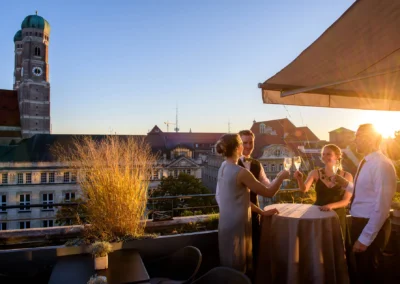 Gäste bei einer Hochzeitsfeier auf der Terrasse des Bayerischen Hofes in München, fröhlich beim Anstoßen.