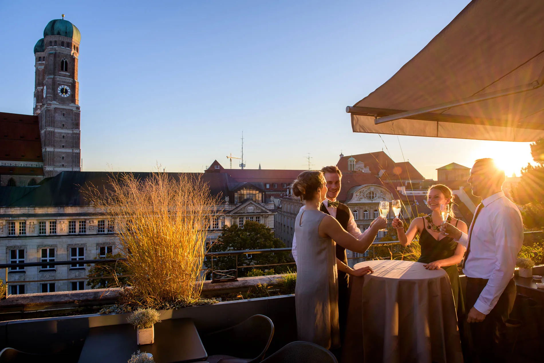 Gäste bei einer Hochzeitsfeier auf der Terrasse des Bayerischen Hofes in München, fröhlich beim Anstoßen.