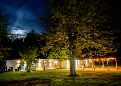 Nächtliche Szene der Hochzeitslocation im Waldhaus Alte Tram bei Muenchen, beleuchtete Gebäude und Bäume.