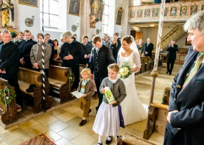 Braut mit Blumenstrauss und Kindern in Kirche bei Hochzeitsfeier in Valley nahe Holzkirchen. Hochzeitsreportage.