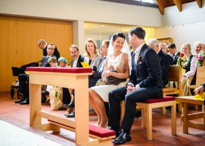 Braut mit Baby und Bräutigam bei der kirchlichen Trauung in Feldafing am Starnberger See, Hochzeitsfotografie.