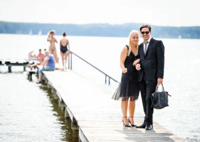 Elegant gekleidetes Paar auf Holzsteg am Starnberger See bei einer Hochzeit, fokusiert auf Hochzeitsfotografie.