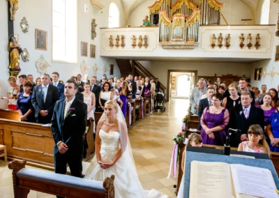 Kirchliche Trauung in Taufkirchen bei München, Brautpaar und Gäste in Kirche, Hochzeitsfotografie bei Zeremonie.