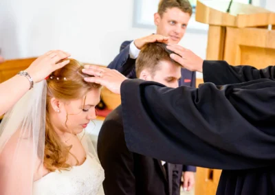 Brautpaar bei kirchlicher Trauung in Oberbayern, gesegnet von Pfarrer. Hochzeitsfotografie aus Garmisch.