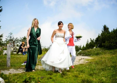 Braut in weißem Kleid und zwei Begleiter bei einer Hochzeit nahe der Kampenwand, aufgenommen für Hochzeitsfotografie.