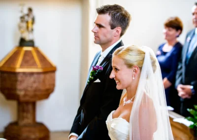 Brautpaar waehrend kirchlicher Trauung in Taufkirchen, laechelnd, Hochzeitsfoto nahe Muenchen.