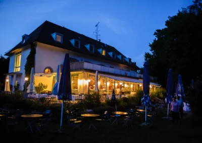 Hochzeitslocation am Abend beim Waldhaus Alte Tram Strasslach, festlich beleuchtet mit Terrasse und Garten.