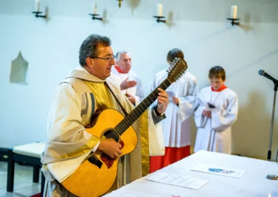 Priester spielt Gitarre bei kirchlicher Trauung in St. Vitus Gilching, begleitet von Messdienern. Hochzeitsfotografie.