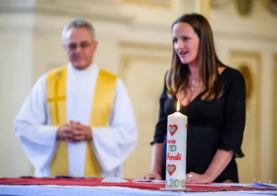 Priester und Frau bei kirchlicher Trauung nahe Bad Toelz, Kerze im Vordergrund. Hochzeitsfotografie Kloster Benediktbeuern.