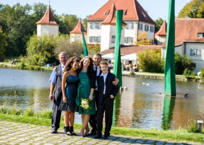 Familiengruppe bei Hochzeit am Schloss Blutenburg, München. Hochzeitsfoto mit idyllischem See im Hintergrund.