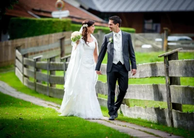 Brautpaar spaziert Hand in Hand auf einem Weg bei einer Hochzeit in Sauerlach-Arget, festgehalten in einem Hochzeitsfoto.
