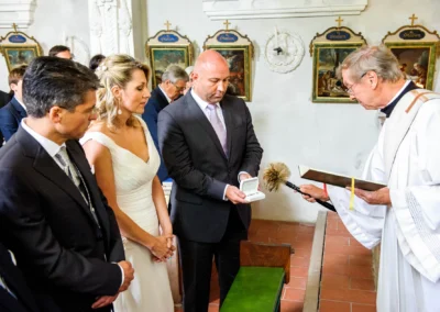 Brautpaar bei Trauung mit Priester, Hochzeitsreportage in Kirche, Sankt Quirin Gmund, festlicher Moment.