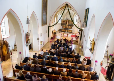 Kirchliche Trauung in St. Vitus Gilching, Hochzeitsreportage zeigt Gaeste und Brautpaar in der Kirche.
