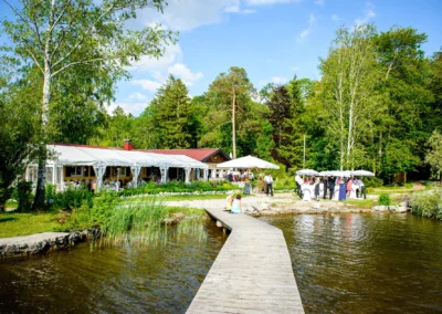 Hochzeitsreportage am Starnbergersee: Seesteg, Feier im Garten unter Pavillons mit Baeumen und See im Hintergrund.