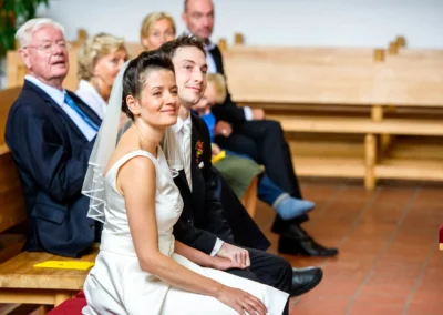 Brautpaar bei kirchlicher Trauung in Feldafing, umgeben von Gaesten. Hochzeitsfotografie, Starnberger See.