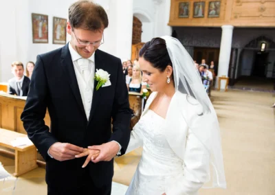 Bräutigam steckt Braut Ring an, Trauung in Aufkirchen. Hochzeitsfotografie in Kirche südlich von München.