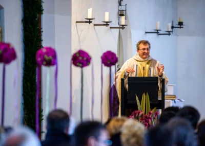 Priester bei kirchlicher Trauung in St. Vitus Gilching, lila Blumen im Vordergrund, Hochzeitsreportage.