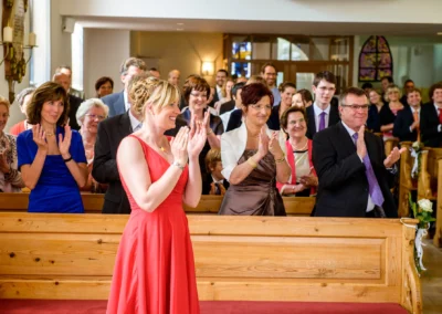 Gäste applaudieren in der Kirche während der Trauung in Oberbayern, Hochzeitsfotografie in Garmisch von Hochzeitsreportage.
