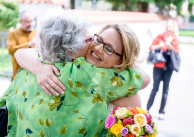 Umarmung bei Hochzeit in München Schwabing, lachende Braut mit Blumenstrauss, Hochzeitsreportage.