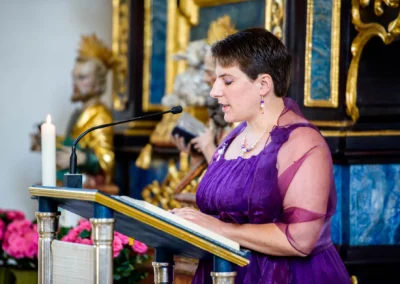 Frau liest bei kirchlicher Trauung in Taufkirchen nahe Muenchen. Hochzeitsfotograf haelt Besonderheiten fest.