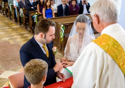 Bräutigam steckt Braut den Ring an in einer Kirche nahe Fischbachau, Hochzeitsfotografie festgehalten.