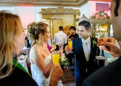 Brautpaar und Gaeste stoßen mit Sekt bei einer Hochzeit in Muenchen an, festgehalten von Hochzeitsfotograf.