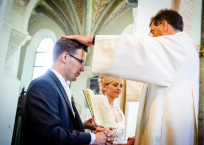 Priester segnet Brautpaar bei kirchlicher Hochzeit im Kloster Seeon. Hochzeitsreportage in Oberbayern.