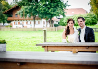 Brautpaar sitzt bei Hochzeitsfoto in Garten vor Bauernhaus in Arget, Kreis München.