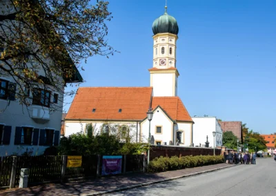 Kirchliche Trauung in Grosshadern, Hochzeitsreportage. Kirche mit Turm, Hochzeitsgesellschaft auf der Strasse.