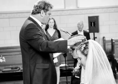 Pfarrer segnet Brautpaar bei kirchlicher Trauung in evangelischer Friedenskirche, festgehalten von Hochzeitsfotograf.